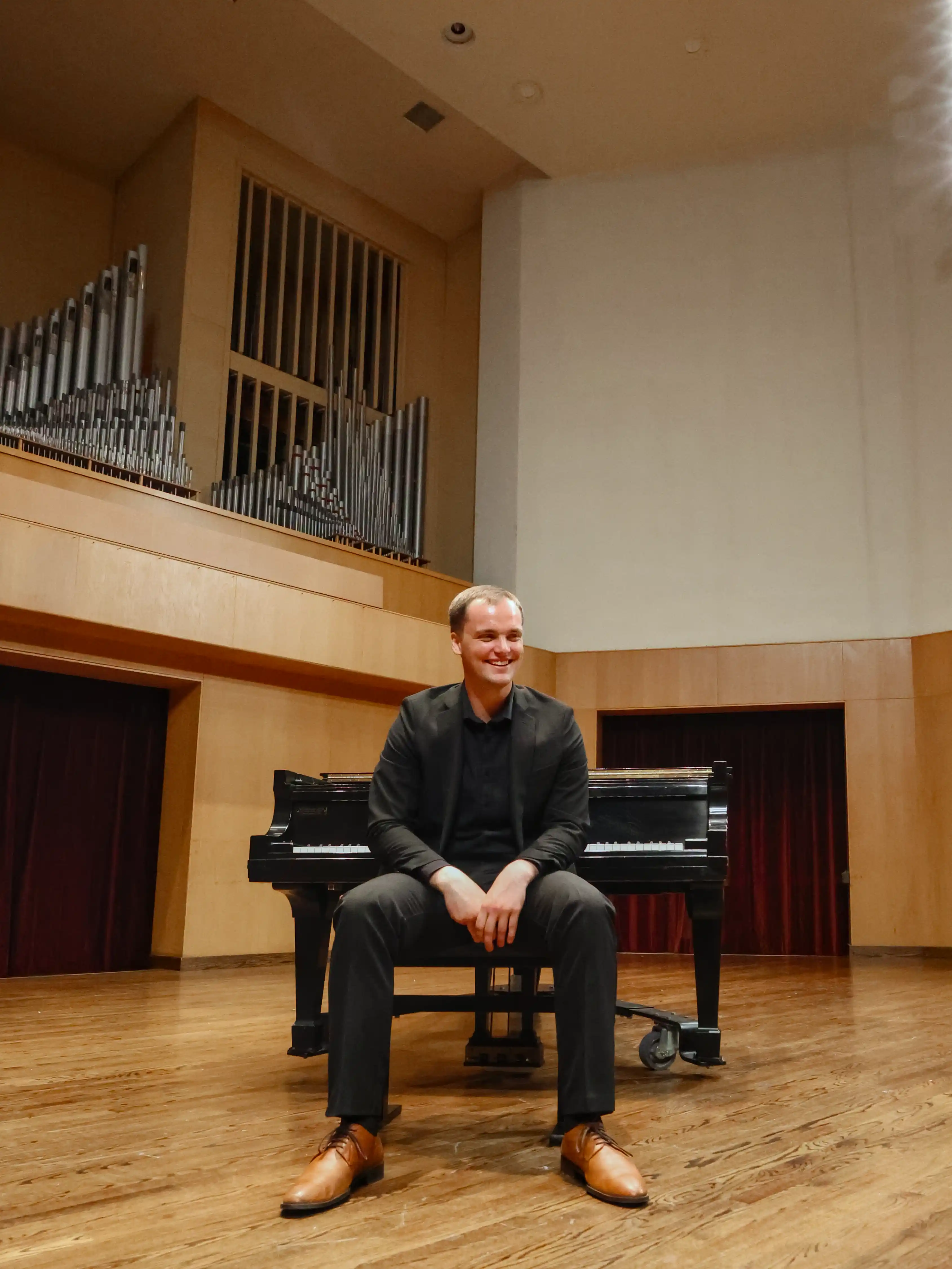 Joshua Beacom sitting in front of a concert piano